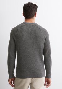 Šedý žebrovaný svetr s dlouhými rukávy, kulatým výstřihem a texturovanou látkou. Má přiléhavé manžety a štítek u lemu.