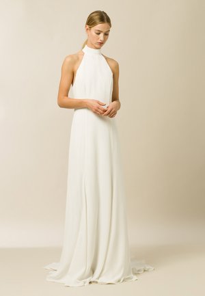 Robe halter blanche avec un col haut et un tissu fluide. Présente une jupe longue avec une texture lisse et des drapés subtils.