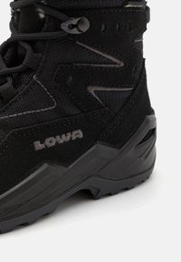 Black hiking boot featuring a textured suede upper, reinforced toe, rubber outsole, and discreet branding. Designed for durability and traction.