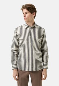 Gestreept shirt met lange mouwen in beige en marineblauw. Voorzien van een knoopsluiting bij de kraag, een borstzak en contrasterende gestreepte manchetten. Gemaakt van katoen.