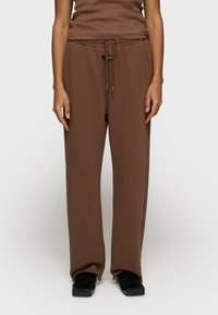 Bruine sweatpants van katoenmix met een relaxte pasvorm, elastische tailleband en koord. Rechte voorkant zonder zichtbare patronen of accenten.