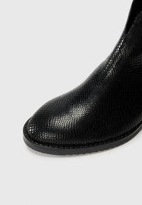 Black ankle boot with a textured snakeskin pattern, pointed toe, and elastic side accents. Smooth surface and a durable rubber sole.