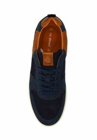 Marineblauwe suède sneaker met bruine gaasaccenten, met een bruine label op de tong en donkerblauwe veters, tegen een witte achtergrond.