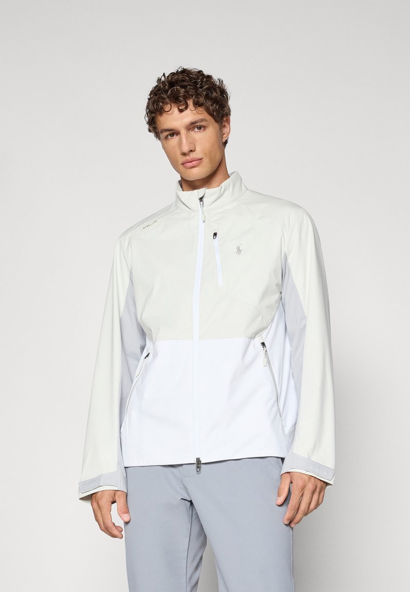 Lightweight, two-tone jacket in gray and white, features a zippered front, high collar, and side pockets with smooth texture and minimal branding.