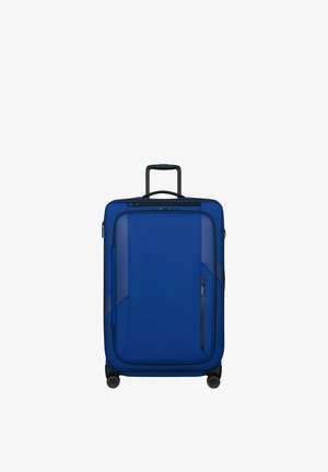 Blue upright suitcase with telescopic handle, front zipper pocket, and four black wheels with red accents on a white background.