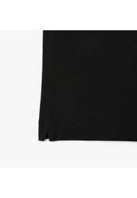 Tejido negro con una superficie texturizada, con un corte recto y aberturas laterales en el dobladillo para facilitar el movimiento.