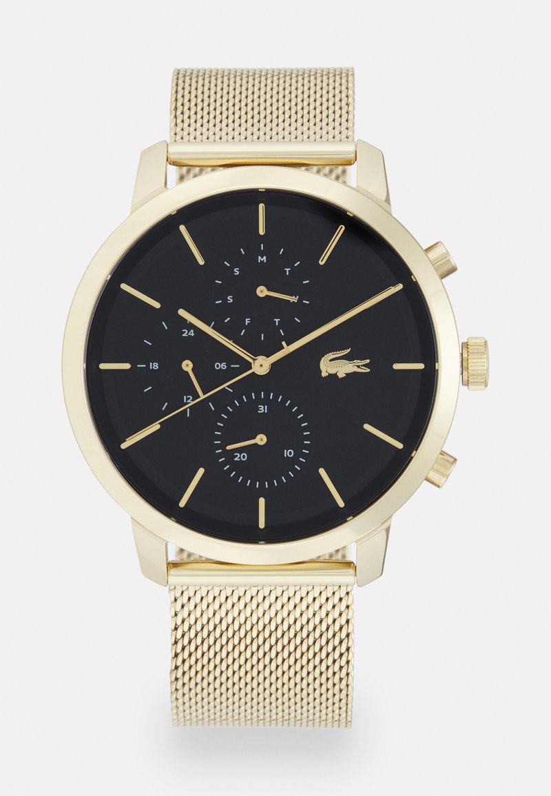 Montre en métal doré avec un bracelet en maille et un cadran noir. Elle comprend trois sous-cadrans, des marqueurs d'heure et un logo de crocodile.