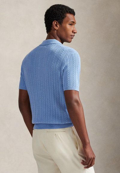 Krótki rękaw sweterkowego polo z jasnoniebieskiej bawełny. Charakteryzuje się prążkowaną fakturą, wzorem warkocza i płaskim kołnierzem. Dopasowany krój z prążkowanym wykończeniem dolnym.