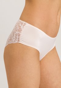 Witte slip met een gladde stof en kanten details aan de zijkanten. De snit is laag met een comfortabele pasvorm en subtiele textuur.