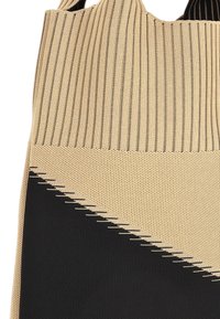 Gebreide draagtas met verticaal gestreept patroon in beige en zwart, met een gestructureerde onderkant en een hoekig ontwerpdetail aan de onderrand.