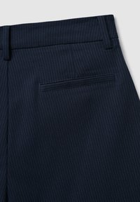 Pantaloni blu navy a righe sottili con una texture liscia, dotati di tasca posteriore e passanti per cintura. Taglio sartoriale con dettagli di cucitura sottili.