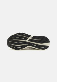 Sport shoe outsole featuring a black rubber design with textured patterns for grip and white midsole accents, emphasizing durability and traction.