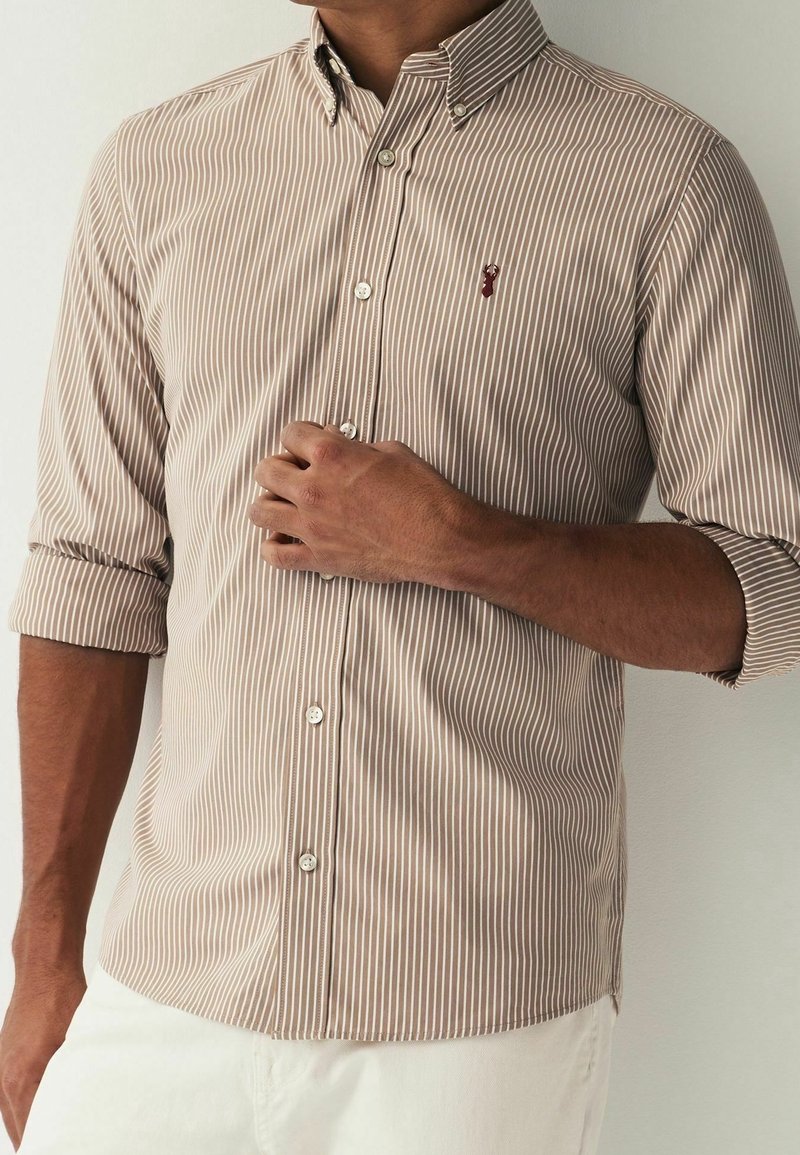 Hemden mit Knopfleiste und dünnen vertikalen Streifen in Beige und Braun, mit klassischem Kragen und kleinem gesticktem Logo auf der Brust.