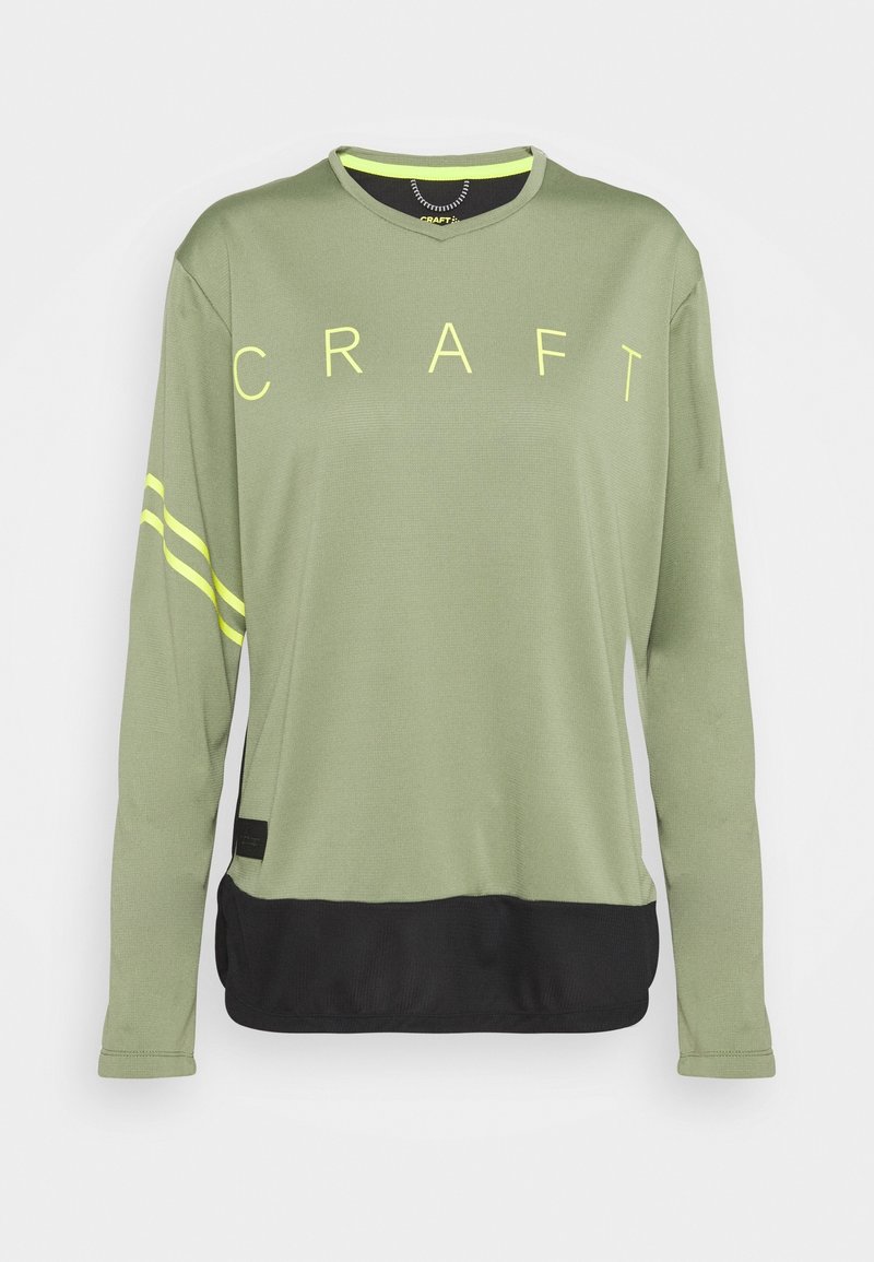 Långärmad idrottströja i olivgrön med "CRAFT"-logotyp. Har svart fåll och gula ränder på ärmarna, gjord av mjukt och andningsbart material.