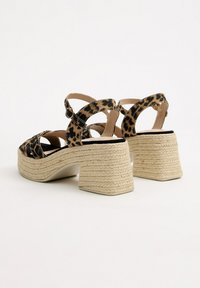 Sandalias espadrilles de estampado de leopardo con un tacón grueso trenzado y correas en los tobillos. La plantilla es acolchada y el diseño cuenta con la punta descubierta.