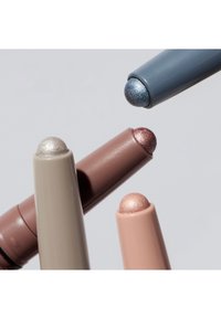 Quatre crayons de fard à paupières crème métalliques en teintes bleu, argent, bronze et or avec des pointes arrondies sur un fond blanc.