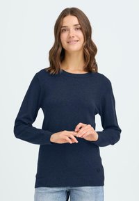 Mörkblå tröja med långa ärmar, rund halsringning och ribbat avslut. Mjuk textur och figursydd design. Har en liten logotyp på vänster sida.