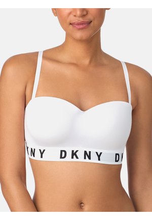 Vrouw draagt een witte strapless beha met dunne verstelbare bandjes en een DKNY-logoband onder de buste.