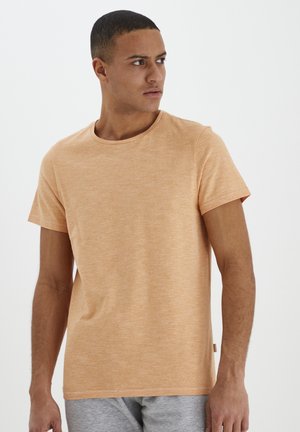 Kortærmet t-shirt med rund hals i lys orange, lavet af tekstureret stof med et subtilt meleret mønster, og med et lille mærke på siden.