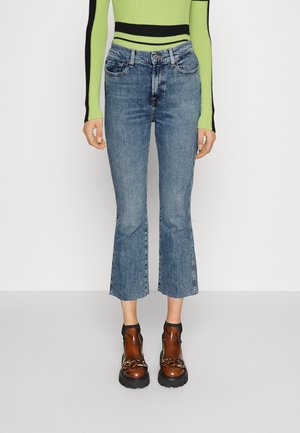 Μπλε τζιν παντελόνι με φλάρε μηρού και ελαφριά πλύση, φθορές και ακατέργαστα τελειώματα. Συνδυασμένο με καφέ μποτάκια μέχρι τον αστράγαλο με αλυσίδες.