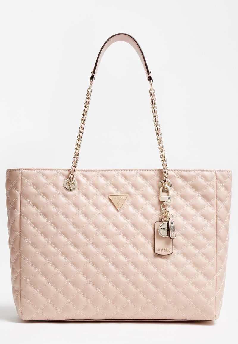 Sac à main rose matelassé avec des lanières en chaîne dorée et un logo triangulaire. Comprend un pendentif avec des étiquettes pour plus de détails. Texture lisse avec une forme structurée.