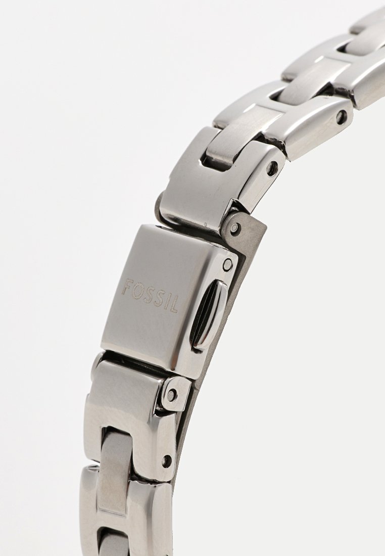 Pulsera de reloj de acero inoxidable con un acabado pulido, que presenta enlaces entrelazados, un cierre de marca y una textura suave.