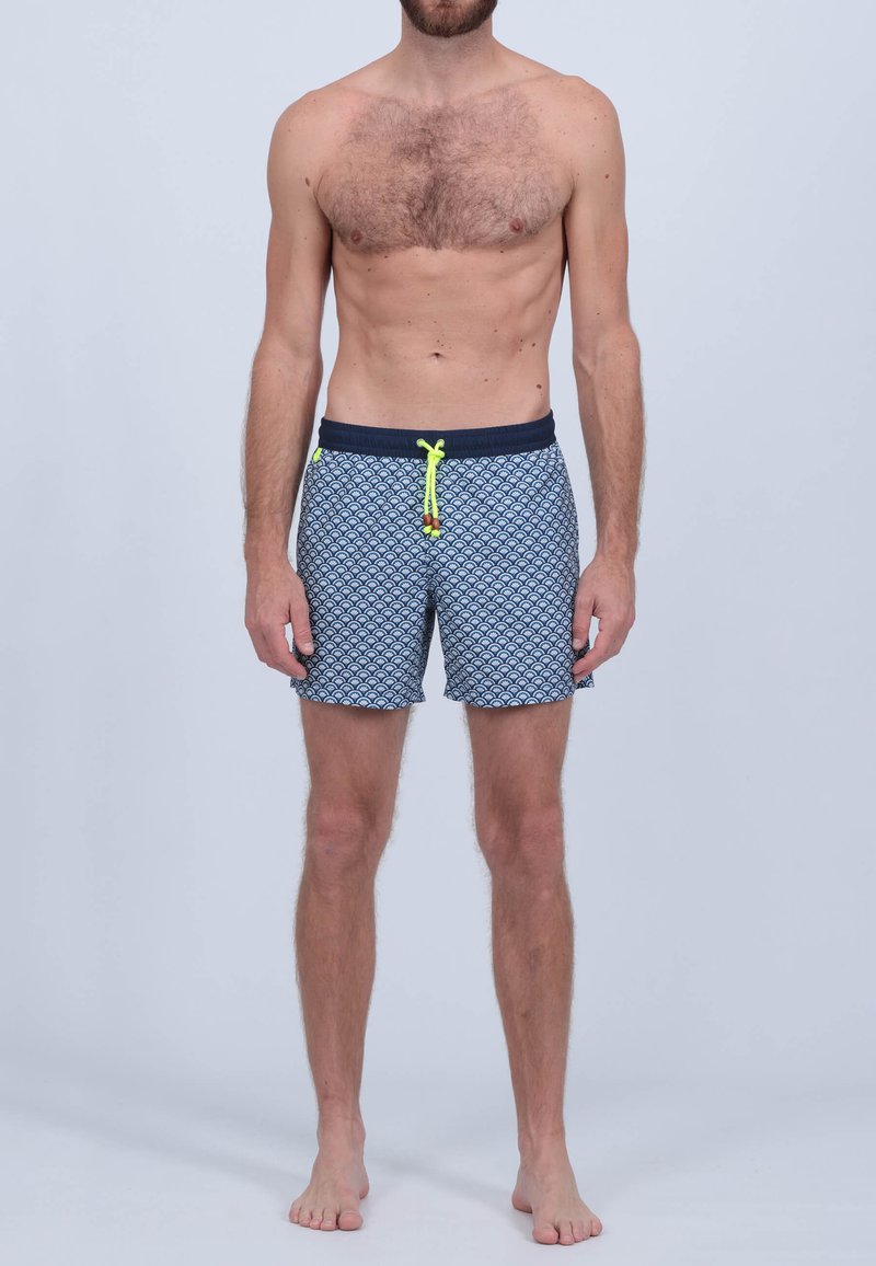 Shorts de bain bleu marine avec un motif de vagues répétées en bleu clair. Dotés d'une taille élastique avec un cordon de serrage jaune vif.