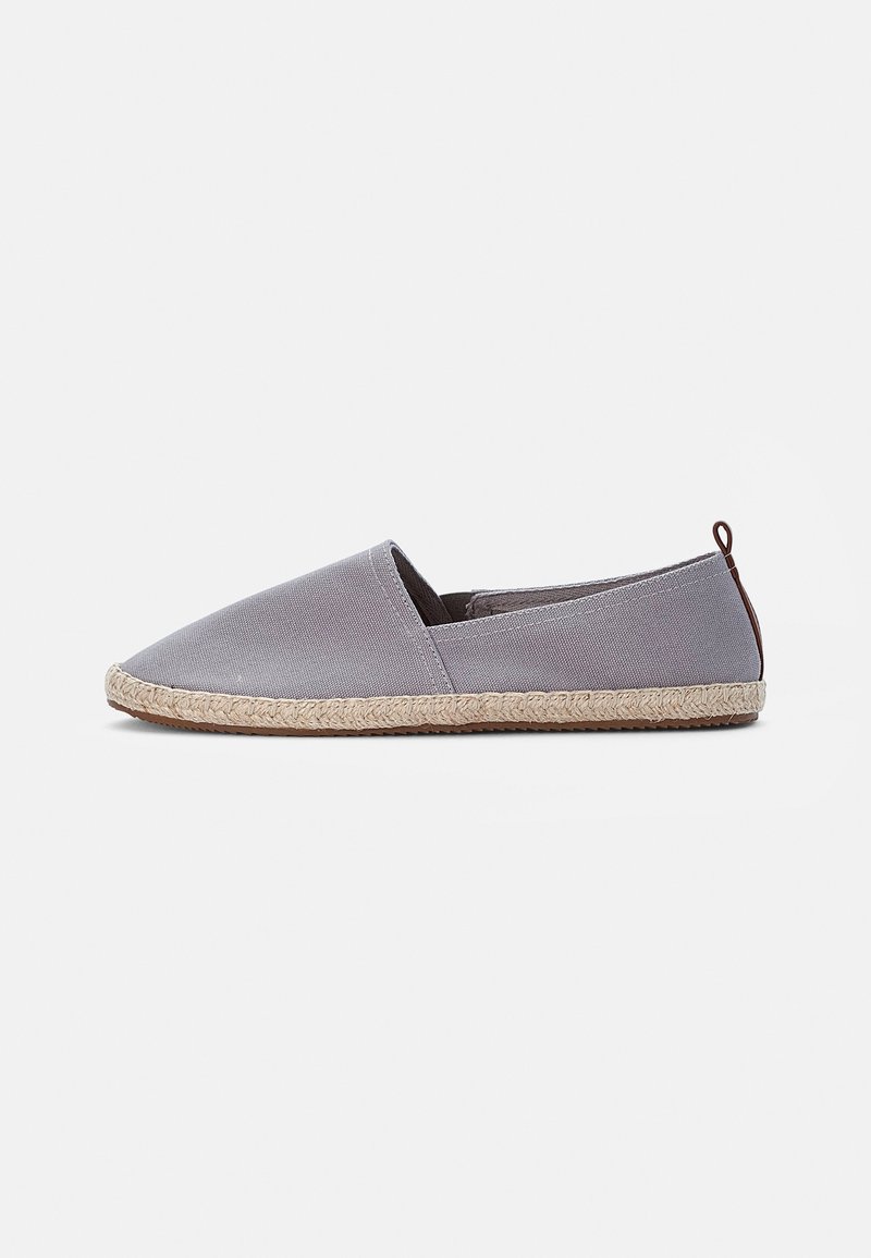 Chaussure espadrille grise claire à enfiler avec semelle en jute tissée et languette marron sur fond blanc, vue de côté.