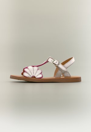 Hvitt og rosa sandaler til småbarn med brun såle, blomstformet frontstropp, ankelstropp med sølvspenne, sidevisning.