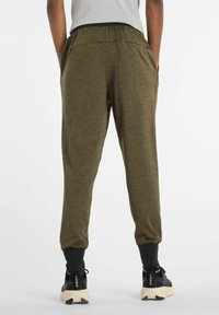 Oliivinvihreät collegehousut, joissa on joustava vyötärö, nilkkakahteet, sivutaskut ja pehmeä tekstuuri, käytetty mustien urheilukenkien kanssa.