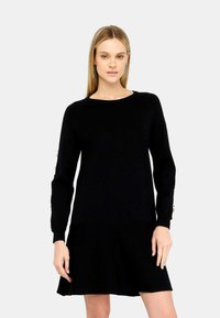 Abito nero lavorato a maglia con corpino aderente, gonna svasata e maniche lunghe con dettagli ai polsini. Tessuto liscio e scollatura a girocollo.