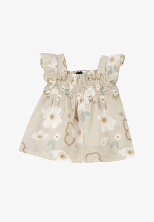 Haut floral pour enfants en tissu léger, avec un fond beige, des fleurs blanches, des feuilles vertes et un détail à volants aux épaules.
