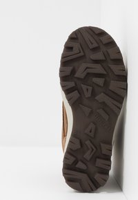 Hnědá semišová podrážka boty s texturovaným, vzorovaným gumovým dnem. Po straně je béžový akcent a embosované logo 'superfit'.