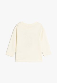 Langärmliges Hemd aus weichem, leichtem Creme-Stoff. Verfügt über einen abgerundeten Halsausschnitt und einen entspannten Schnitt. Einfaches Design ohne sichtbare Muster oder Akzente.