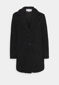 Svart strukturerad kappa med slagkrage, framknäppning med knappar och två fickor. Tillverkad av mjukt, lurvigt tyg med en avslappnad passform.