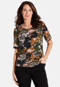 Kurzärmeliges, florales Oberteil in Grün, Braun, Schwarz und Pink. Verfügt über einen runden Ausschnitt und einen lockeren Schnitt mit großen Blumenmustern auf weichem Stoff.