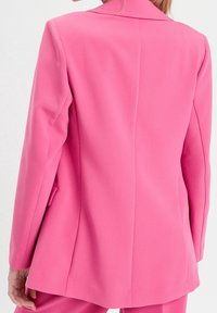 Tilpasset lyserød blazer med en glat tekstur, notch-kraver og en enkelt split bagpå. Har et slankt, moderne design og skræddersyet silhuet.