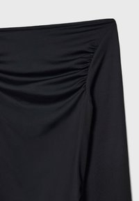Crni rastezljivi top od tkanine s naborima duž prednjeg šava, glatka tekstura i elegantan dizajn. Nema vidljivog hardvera ili akcenata.