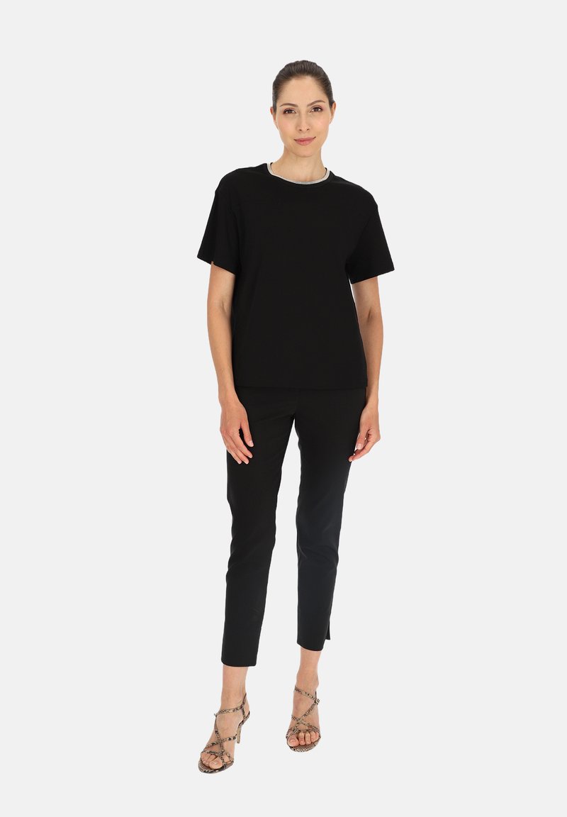 Czarny t-shirt z krótkim rękawem i okrągłym dekoltem, zestawiony z dopasowanymi czarnymi spodniami i sandałami na wysokim obcasie z wężowym wzorem.