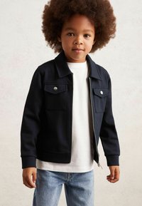 Marineblauwe zip-up jas met twee voorzakken, voorzien van een kraag en ribgebreide boorden. Draag het over een wit shirt. Heeft een gladde textuur en een casual ontwerp.
