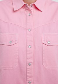Rosa Jeanshemd mit durchgehender Knopfleiste, Druckknöpfen und zwei Brusttaschen. Verfügt über ein klassisches Western-Style Yoke-Design.