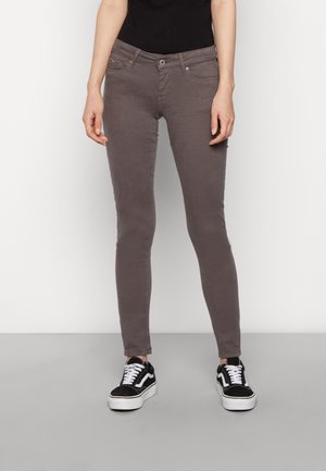 Jeans ajustados grises con una textura suave, que cuentan con cinco bolsillos y un cierre de cremallera. Combinados con zapatillas en blanco y negro.