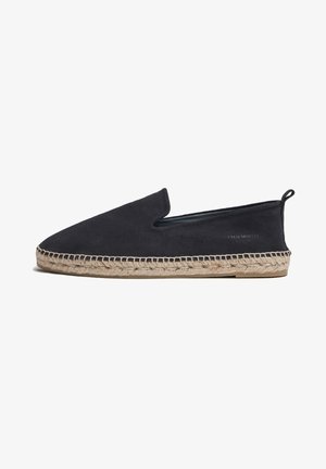 Zapatos de ante negro sin cordones con punta afilada y suela de yute trenzado. Marca sutil en el costado, diseño minimalista con una textura suave.