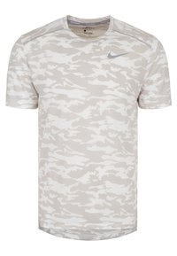 Vaaleanharmaa, naamiointikuvioitu T-paita, jossa pyöreä pääntie ja lyhyet hihat. Rintakehässä pieni harmaa Nike-logo. Pehmeä kangas.