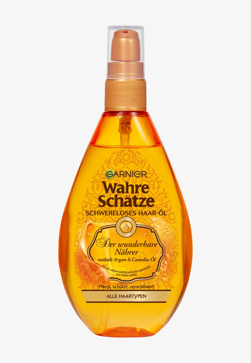 Olej do włosów w kolorze bursztynowym w plastikowej butelce w kształcie kropli z złotą pompką. Etykieta zdobiona misternymi żółtymi wzorami i wyraźnym tekstem.