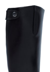Black leather knee-high boot with a top strap featuring a round metallic button on a white background.