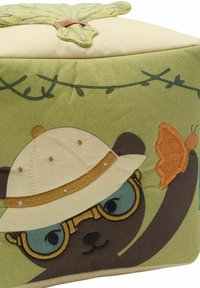 Zöld szövetből készült tároló puff, amelyen egy kalapot és szemüveget viselő medve látható, hímzett részletekkel és egy pillangó díszítéssel az oldalán.