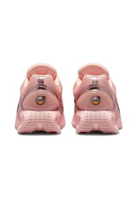 Zapatillas deportivas rosas, parte superior de malla, collar acolchado, acentos en el talón transparente, suela de goma con patrón texturizado y detalles de unidad de aire visible.