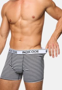 Boxer shorts à rayures noires et blanches avec une ceinture élastique marquée "INDICODE", présentant un design ajusté et une texture de tissu lisse.