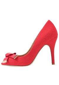 Chaussure à talon haut rouge en tissu texturé, à bout pointu et avec un grand nœud décoratif. Présente un détail en métal doré et un talon fin.